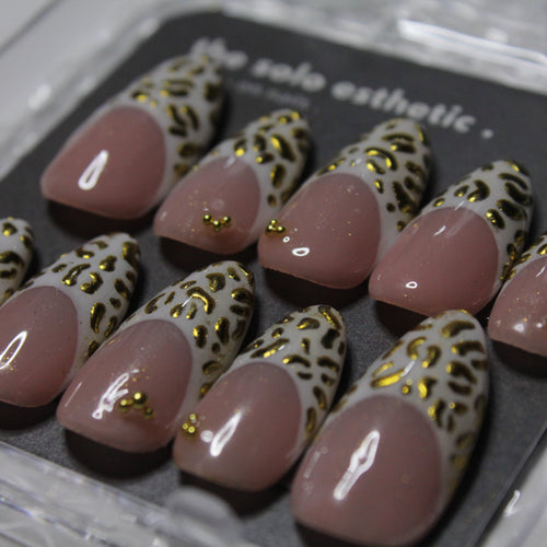 Set of pink nail tips with gold accents on a gray background